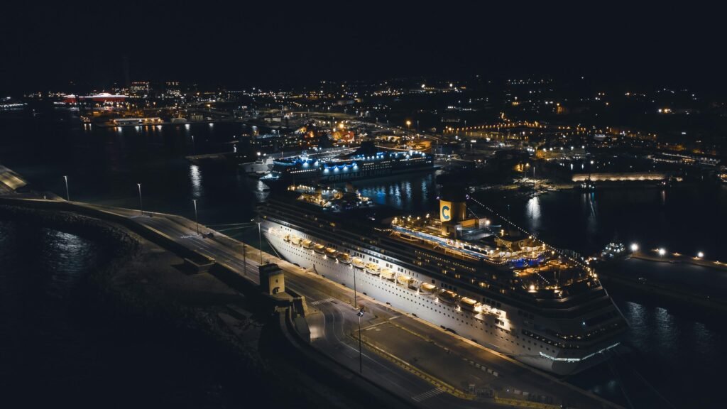 pexels photo 12742592 12742592 Stunning aerial view of a brightly illuminated cruise ship docked in a bustling harbor at night.